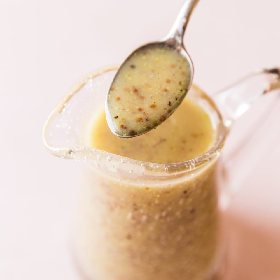 Honey Mustard Salad Dressing in a small pitcher with a spoon