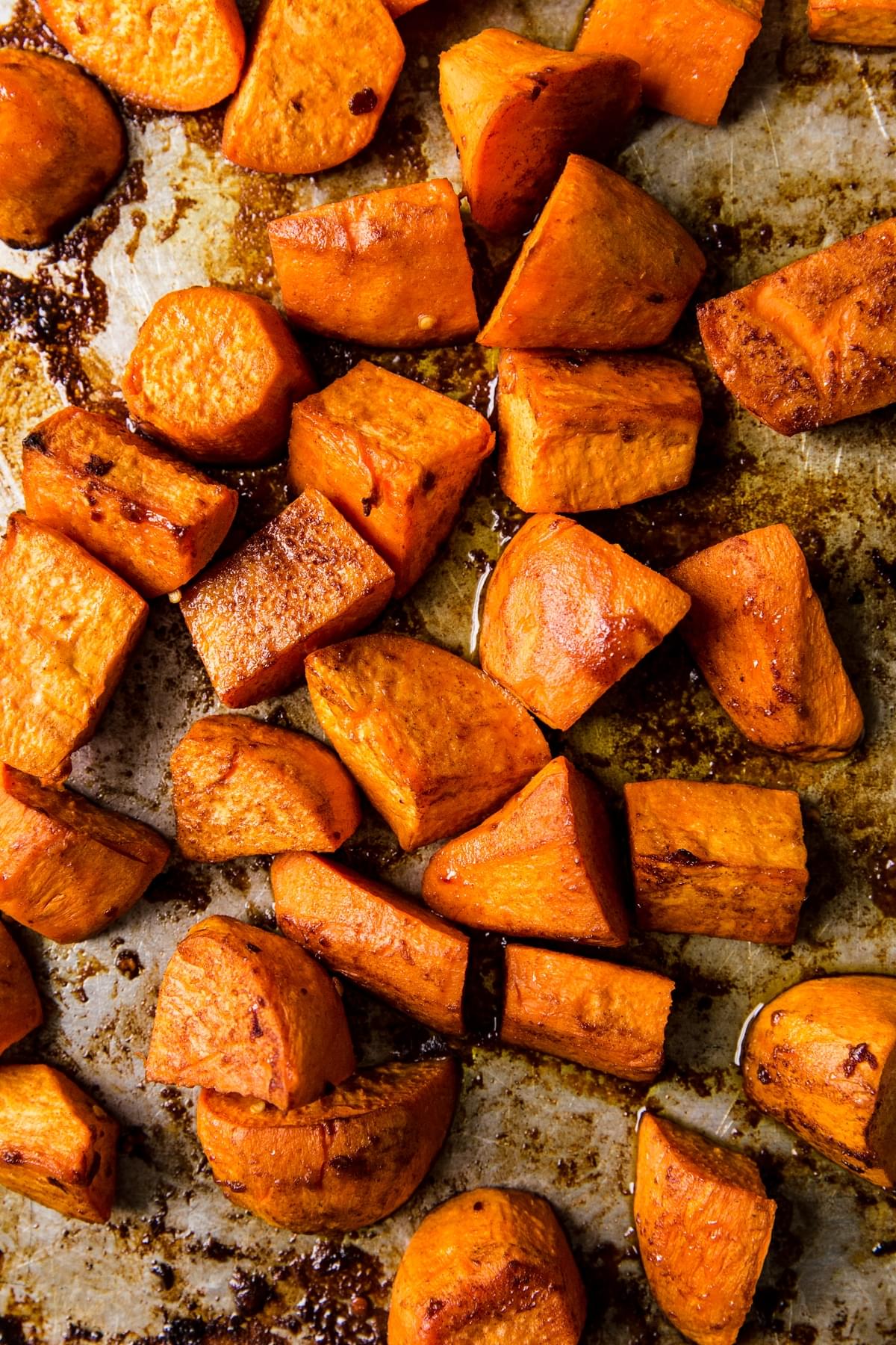 Honey roasted sweet potatoes on a baking sheet with olive oil