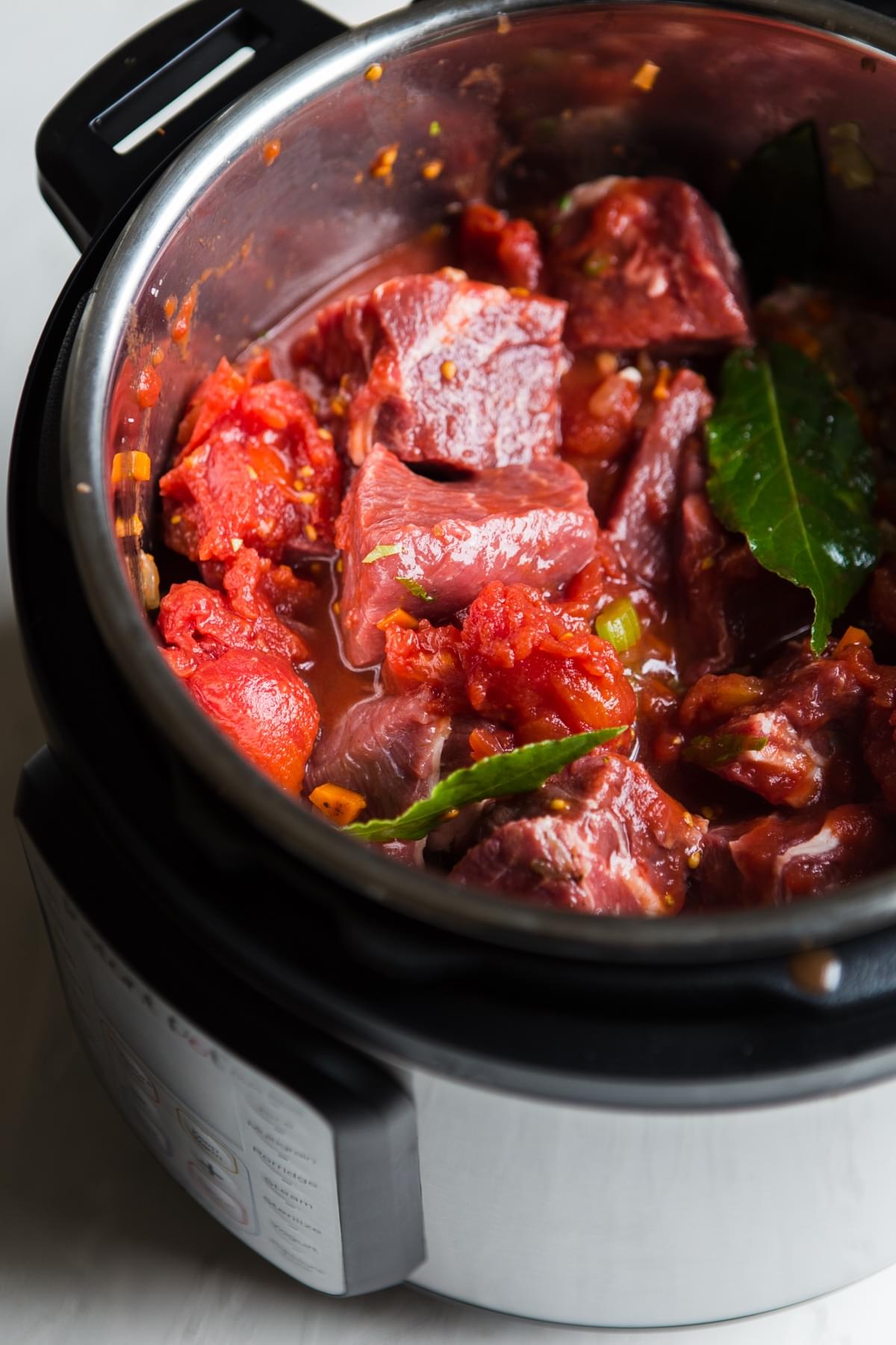 instant pot with raw beef and herbs