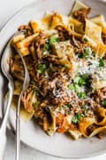 bowl of instant pot beef ragu over pappardelle noodles topped with parmesan cheese