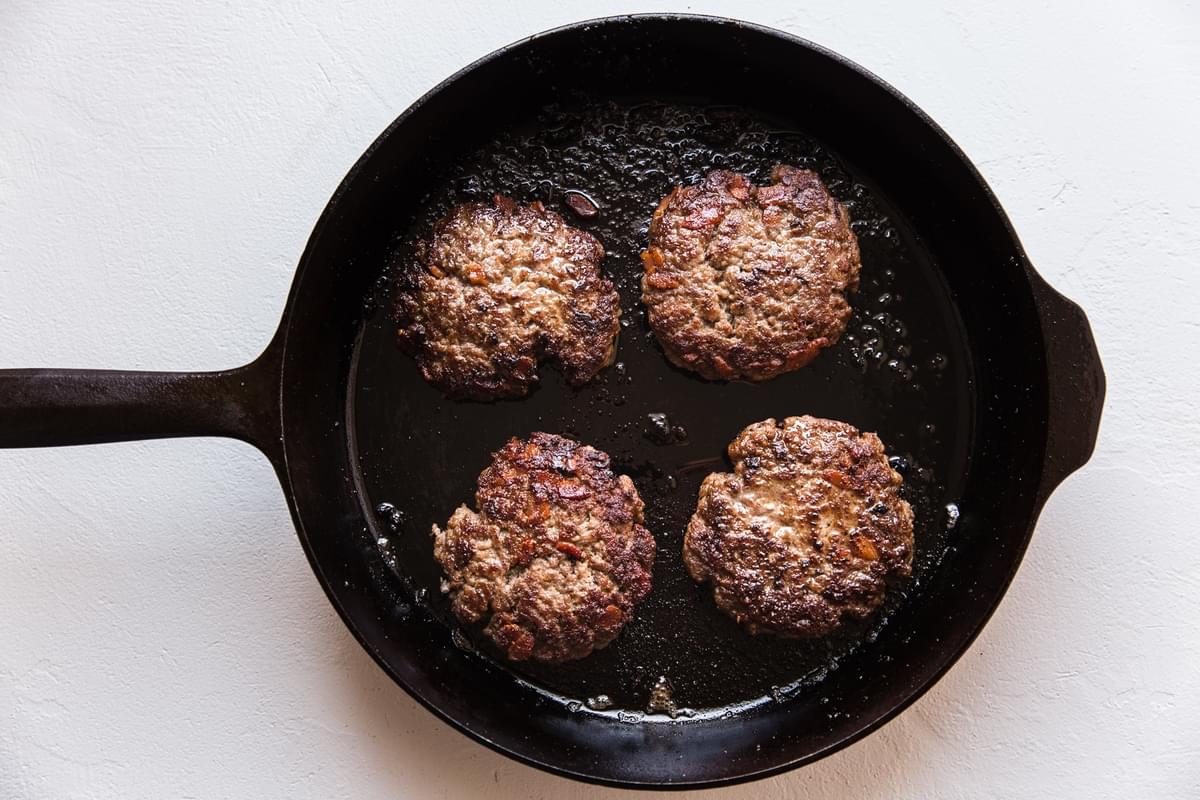 bacon burger patties in a cast iron skillet