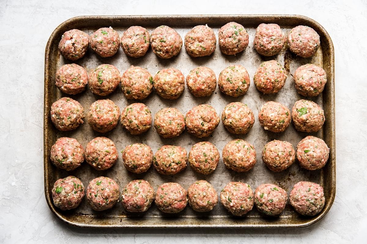 italian meatballs on a sheet pan made with beef, pork, eggs, breadcrumbs, parsley, Parmesan, garlic, salt, and pepper
