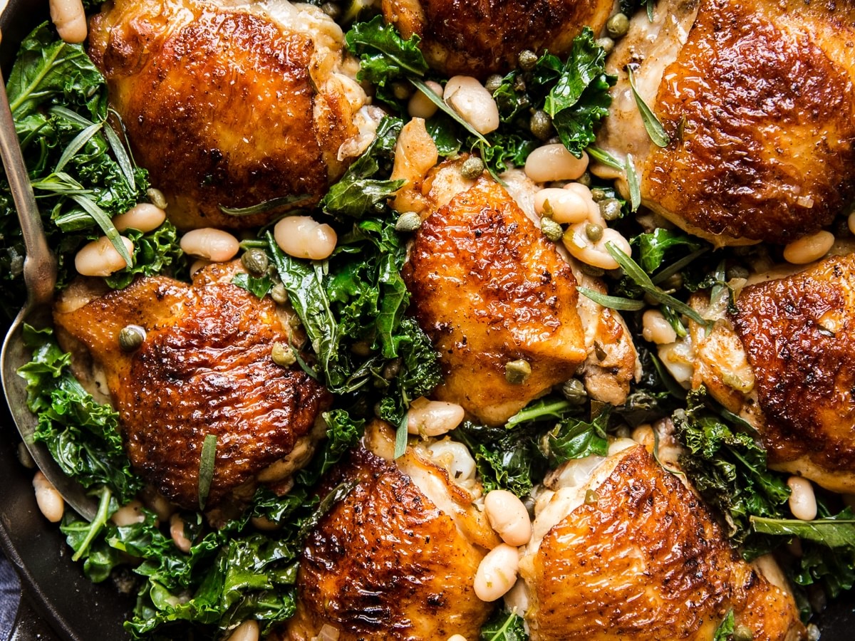 one pot braised chicken and kale with white beans in a cast iron skillet