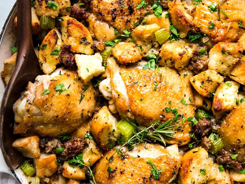 one pot chicken and stuffing casserole in a large braising pan with a wooden spoon