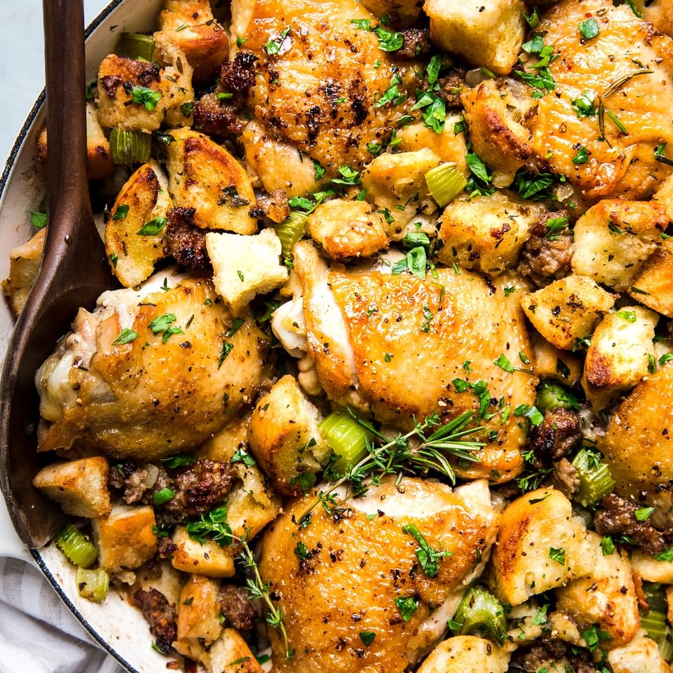 one pot chicken and stuffing casserole in a large braising pan with a wooden spoon