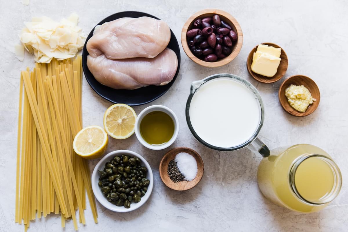 ingredients laid out pasta, chicken breast, olives, cream, stock, lemon
