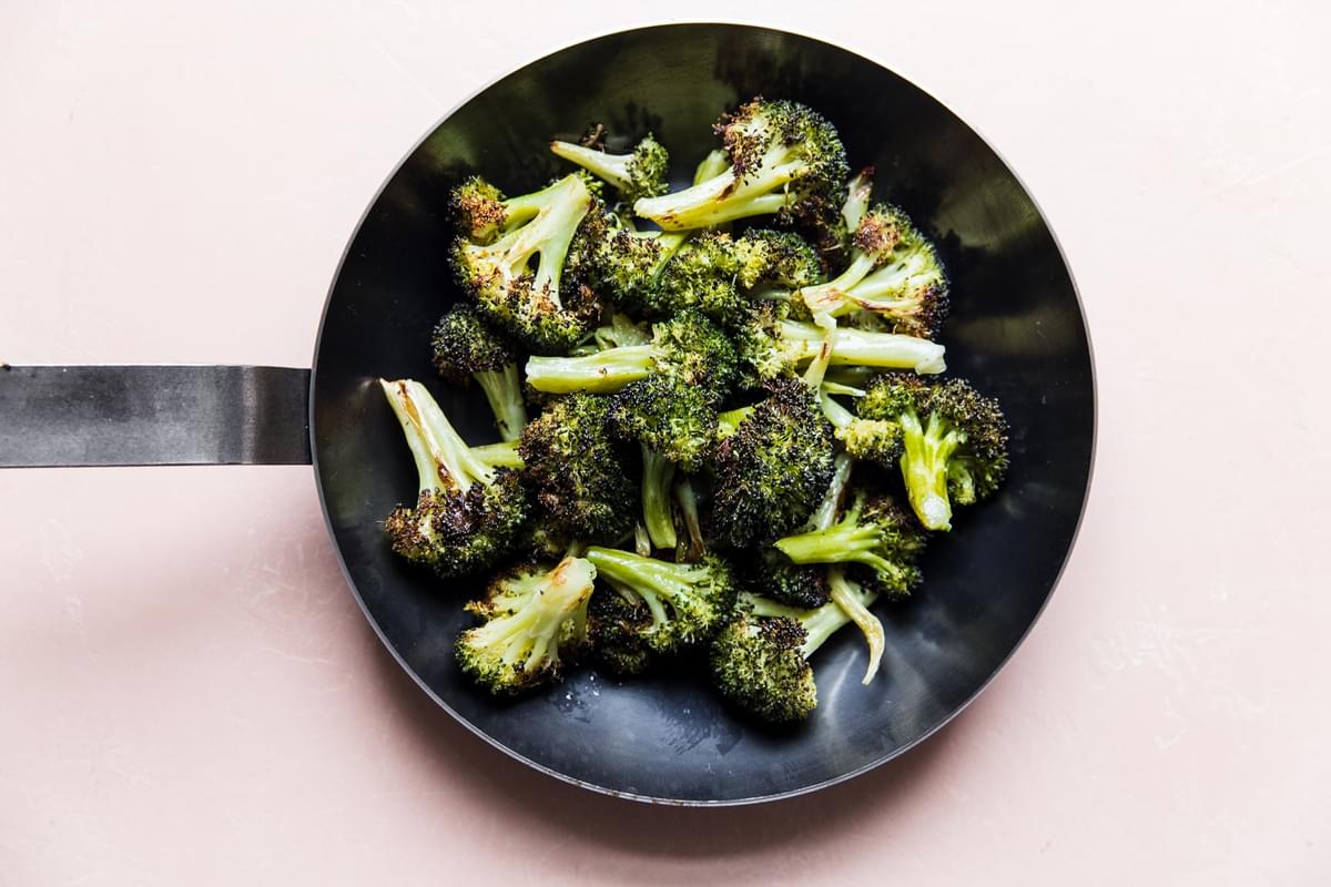 oven baked broccoli being toasted and rewarmed in a skillet to make it even more crispy