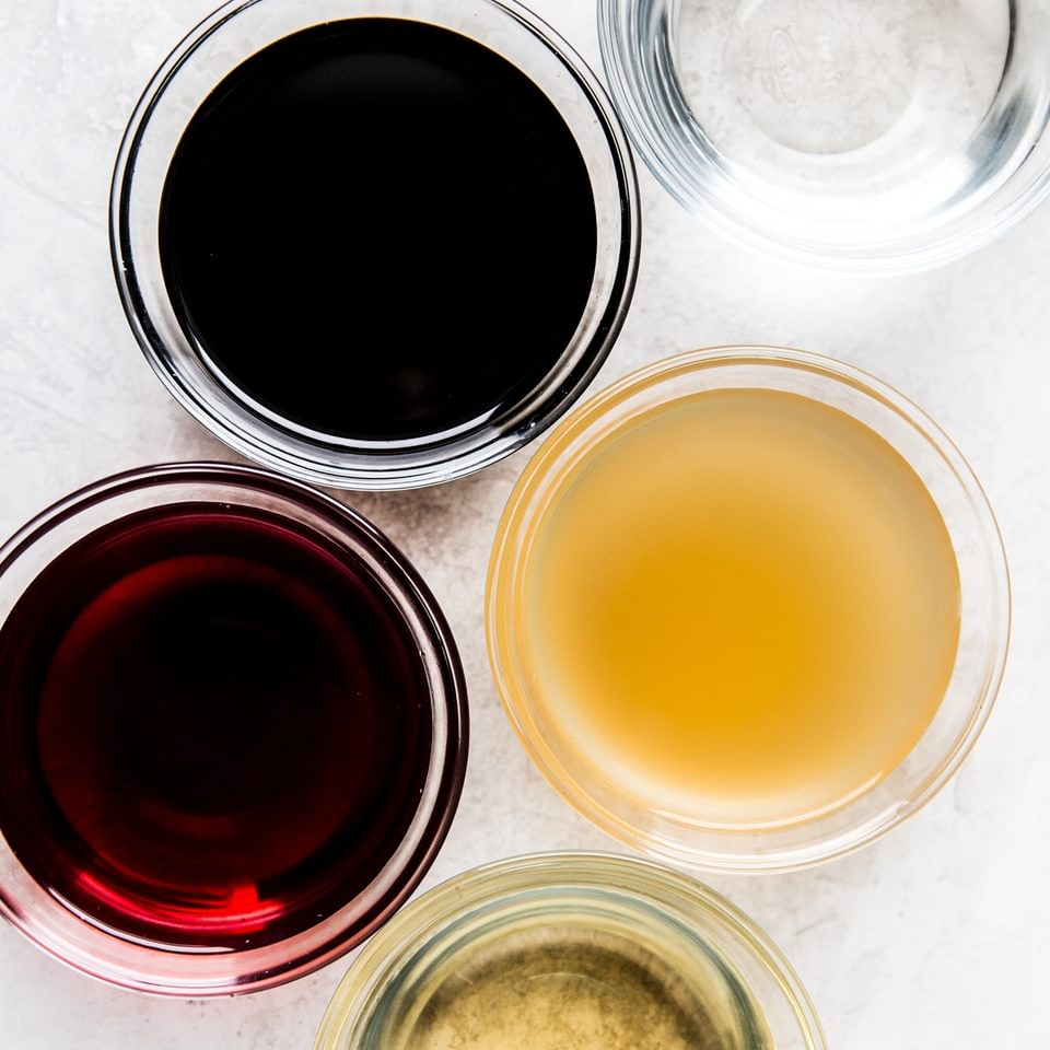White, red, apple, balsamic and white wine vinegars in small bowls.