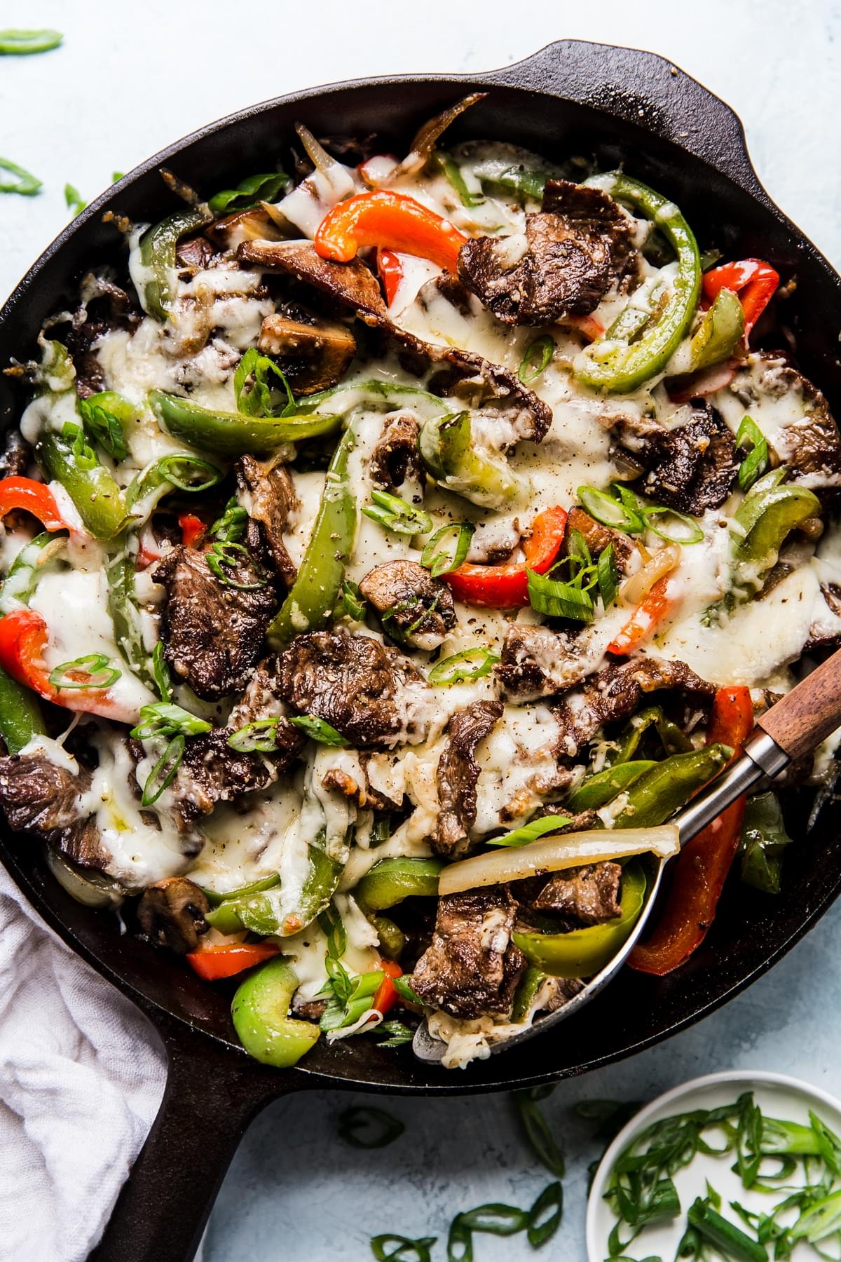 Philly Cheese Steak Skillet in a cast iron skillet with onions, mushrooms, bell peppers and cheese.