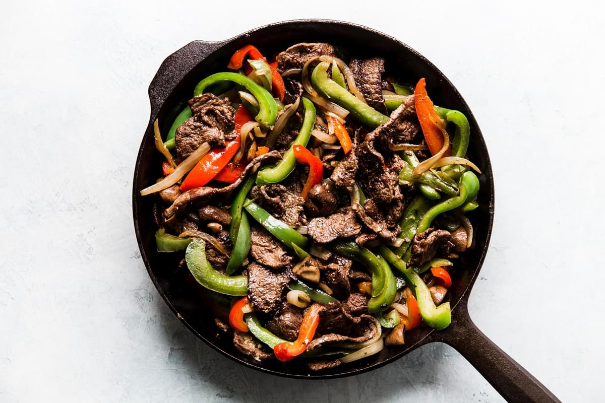 steak, red and green bell peppers mushrooms and onion in a pan