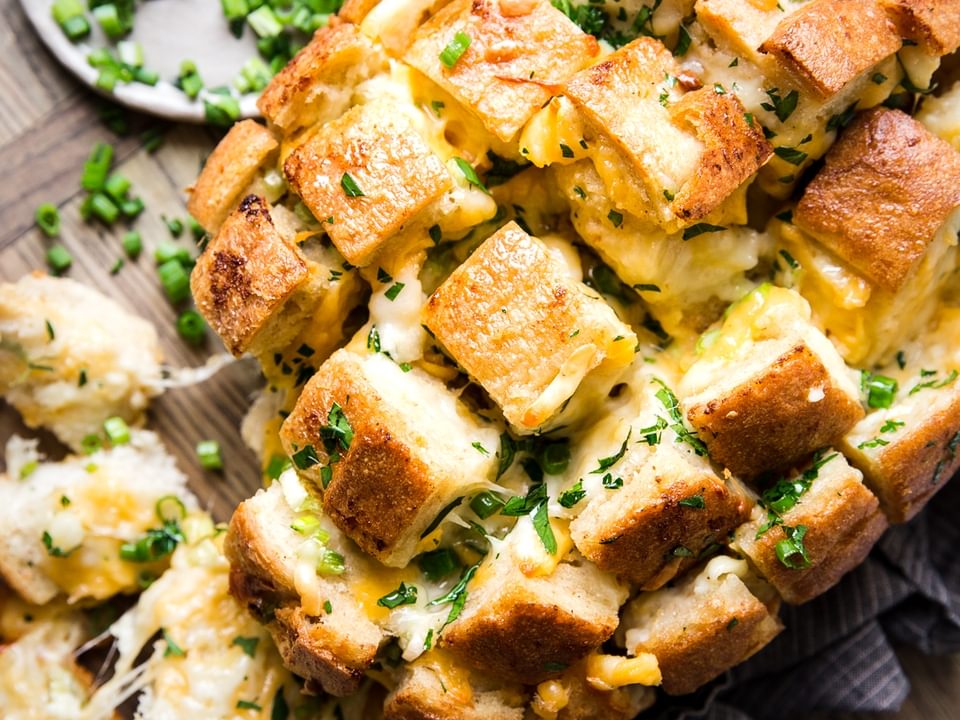 cheesy pull apart cheese bread topped with green onions  on a cutting board