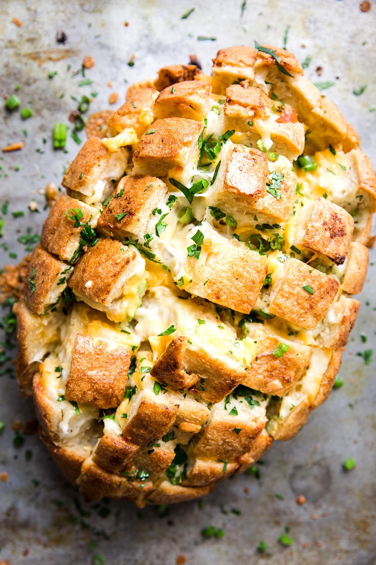 pull apart cheese bread on a sheet pan topped with green onions
