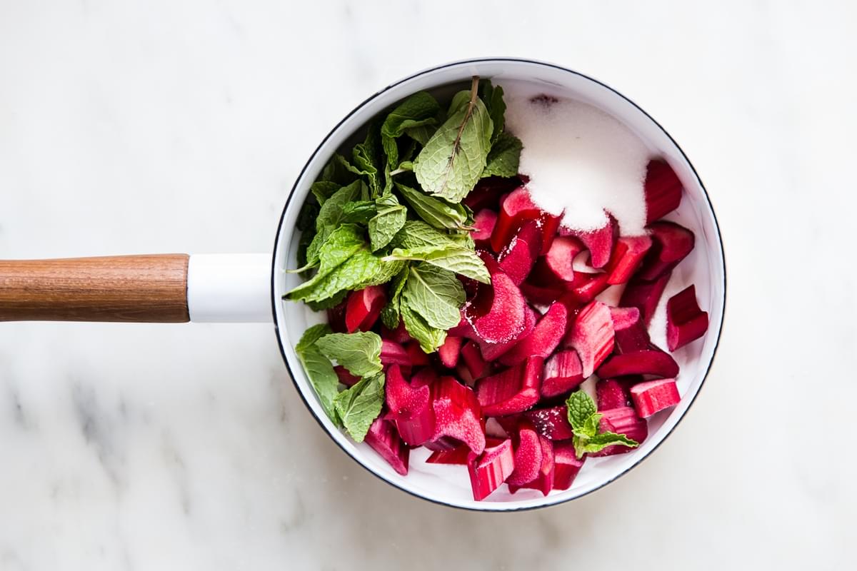 bright red rhubarb, sugar and mint in a sauce pan
