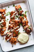 skewered salmon bites on a tray topped with wasabi mayo and fresh cilantro
