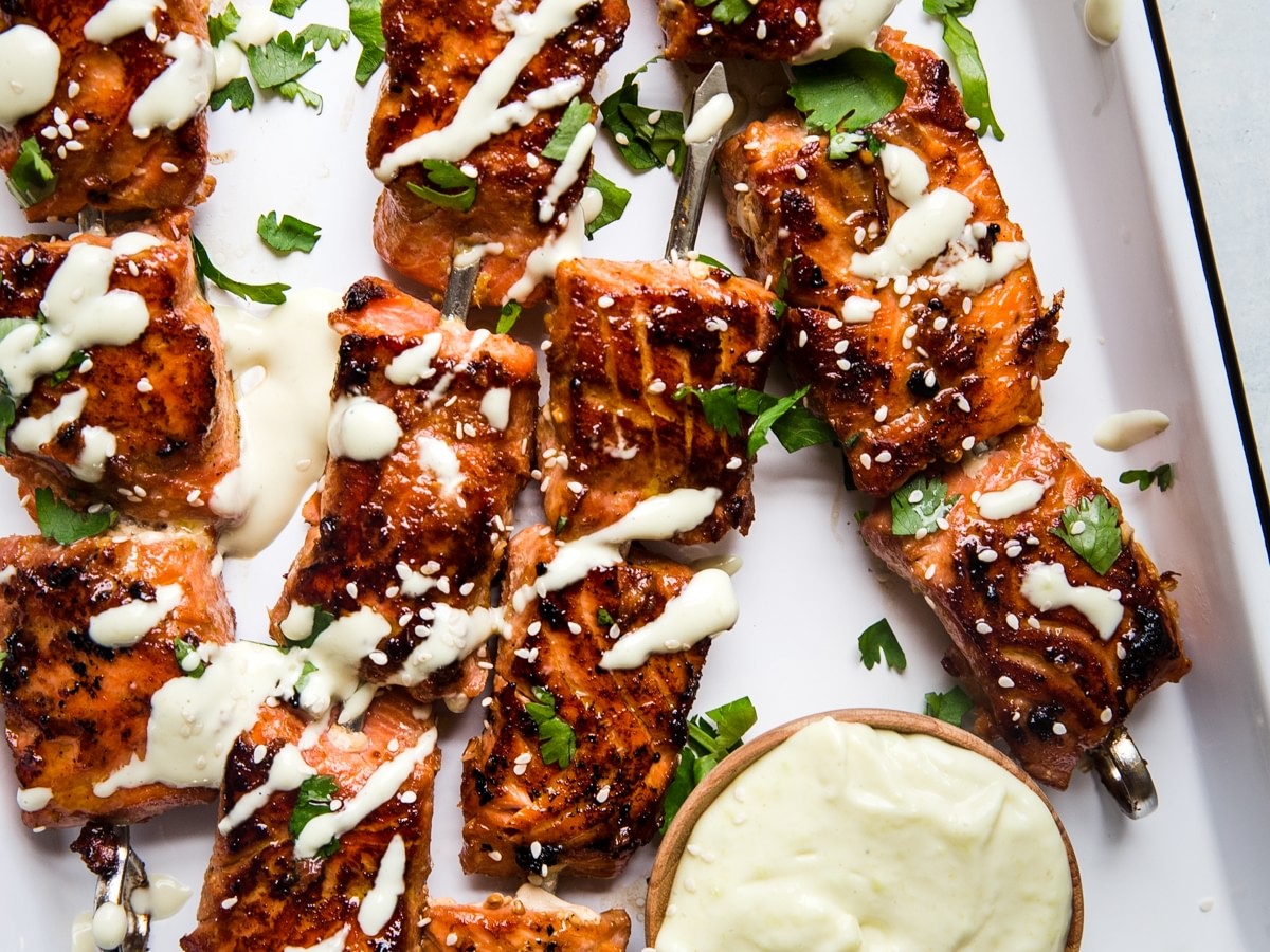 skewered salmon bites on a tray topped with wasabi mayo and fresh cilantro