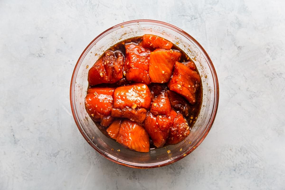 raw salmon bites in a glass bowl with brown sugar, soy sauce, garlic and fresh ginger marinade
