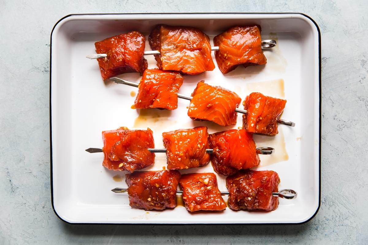 raw salmon bites on skewers marinated in a soy ginger marinade on a tray