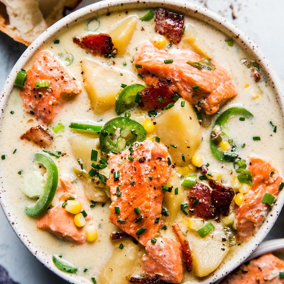 salmon chowder in a bowl with crusty bread on the side