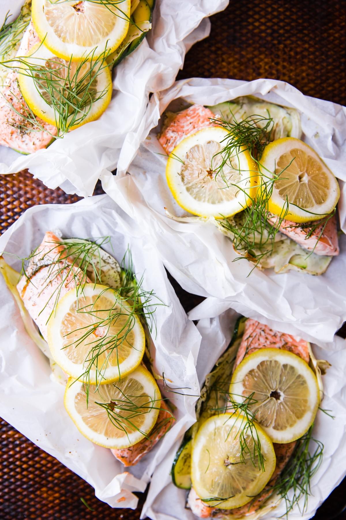 salmon in parchment paper pouches opened and topped with lemon and fennel lemon