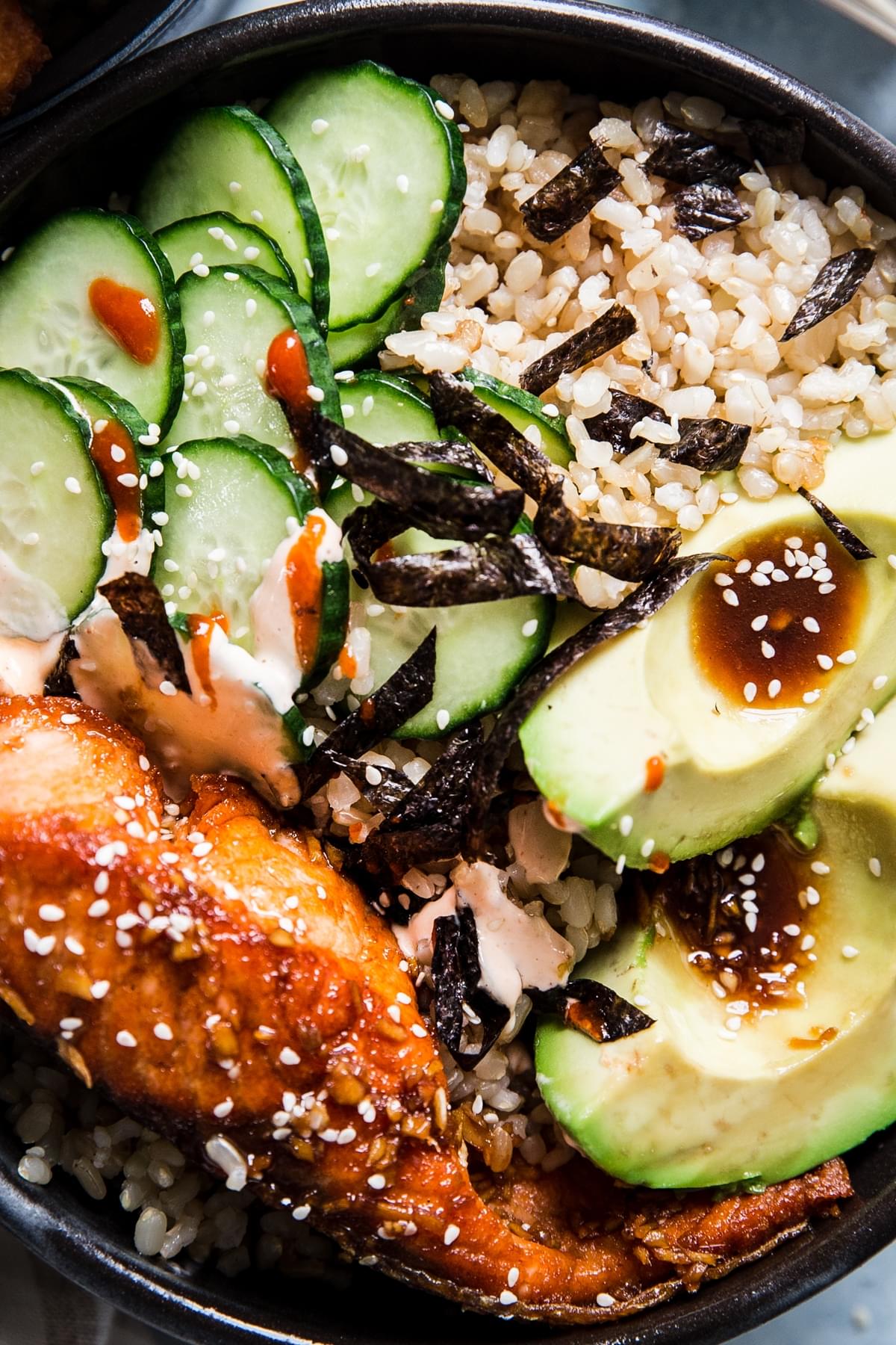 Salmon Sushi Bowl with brown rice, avocado, cucumber, nori, sriracha mayonnaise and sesame seeds