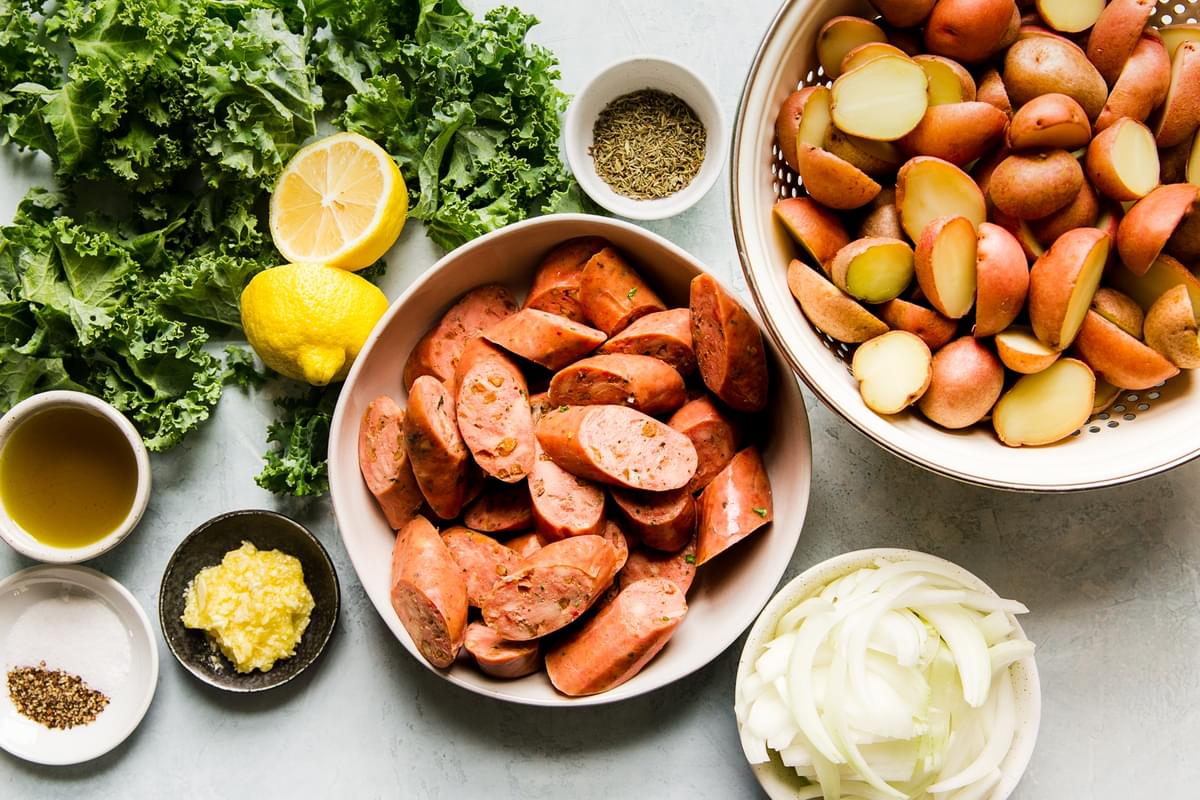 ingredients laid out for Sausage, Kale and Potato Skillet Dinner with onion lemon, oil garlic