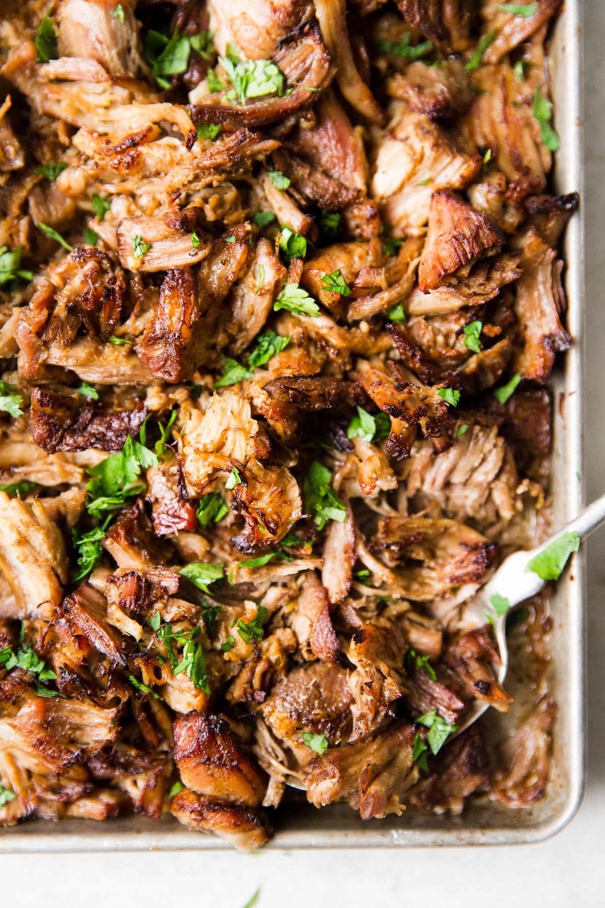 Slow Cooker Crispy Carnitas on a pan with a serving spoon