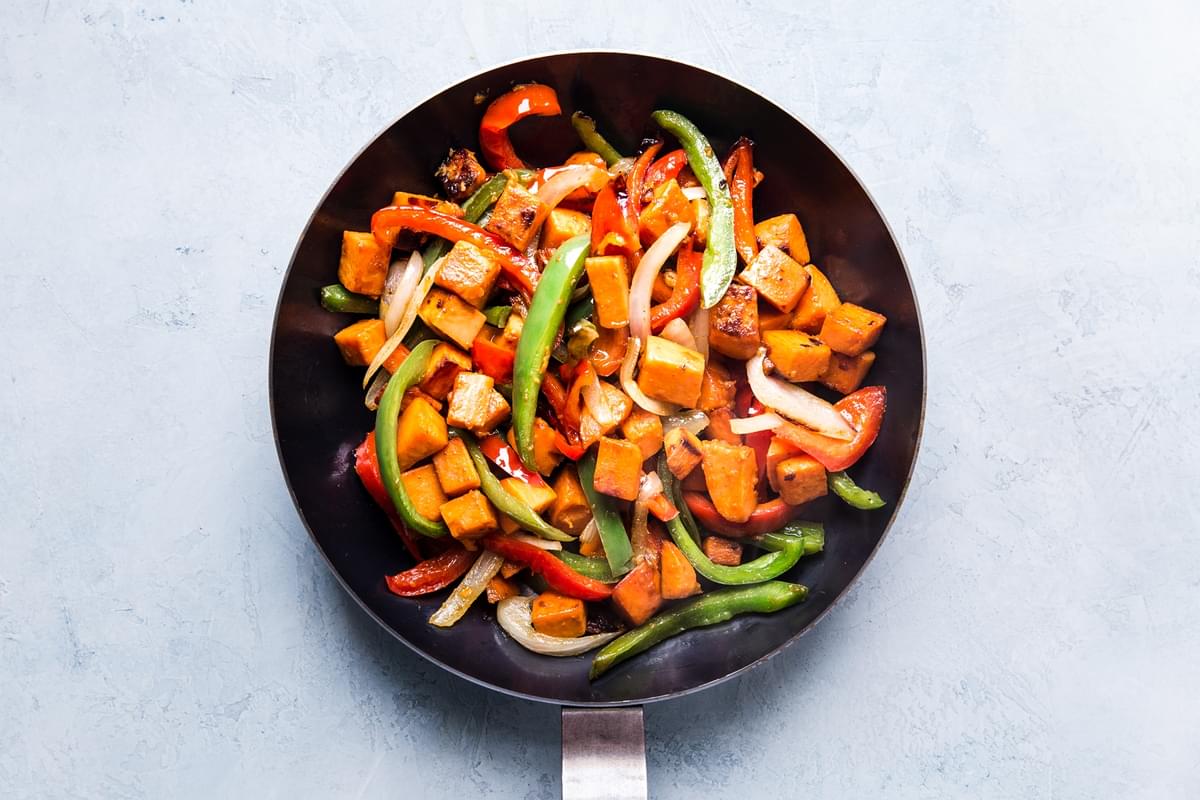 Sweet Potato in a pan with red and green bell peppers and onion