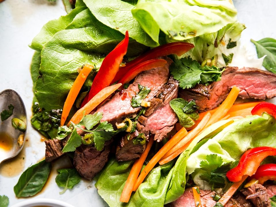 lettuce cups with Thai style steak sliced up, bell peppers, carrots and sauce inside