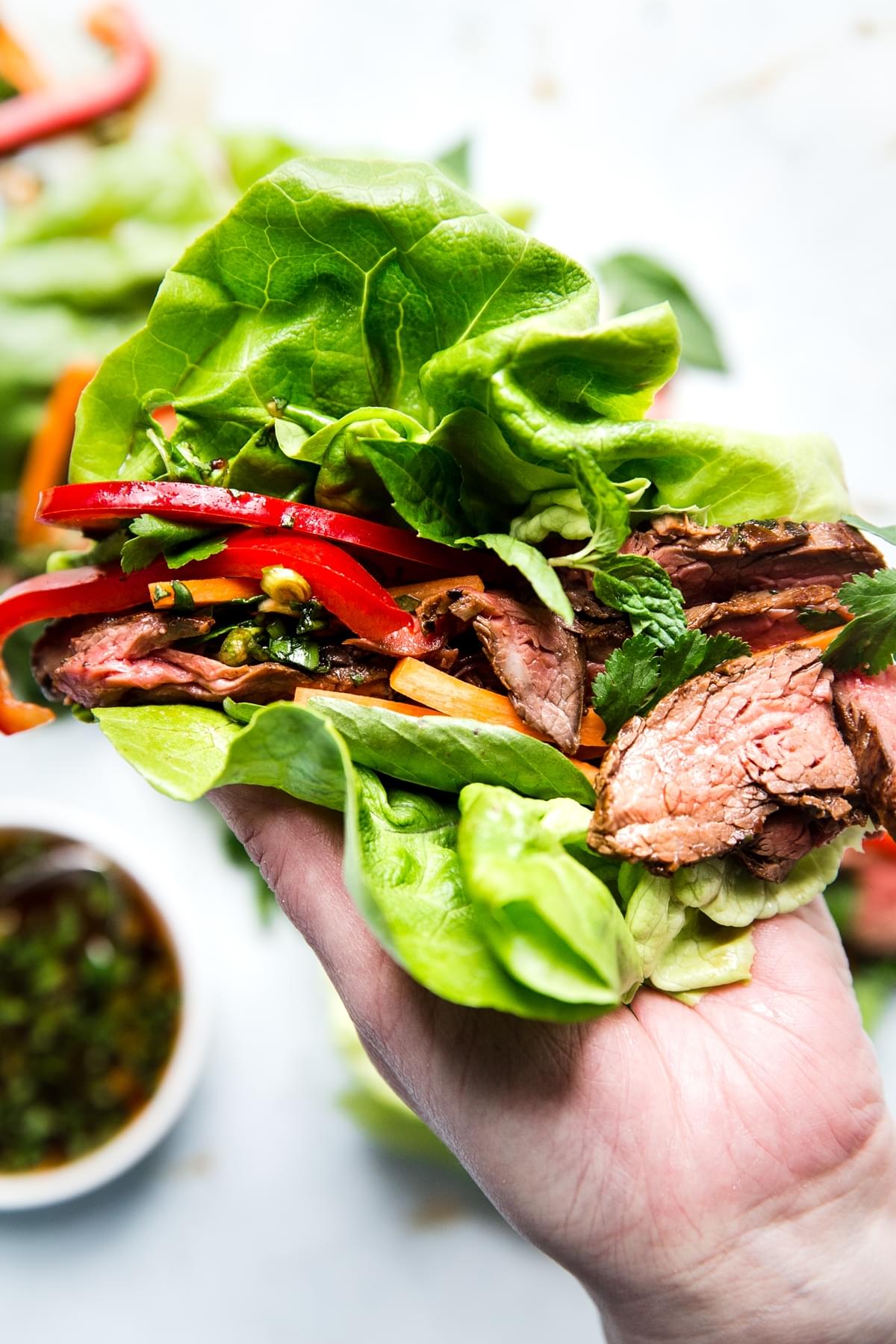 hand holding thai style steak lettuce wraps