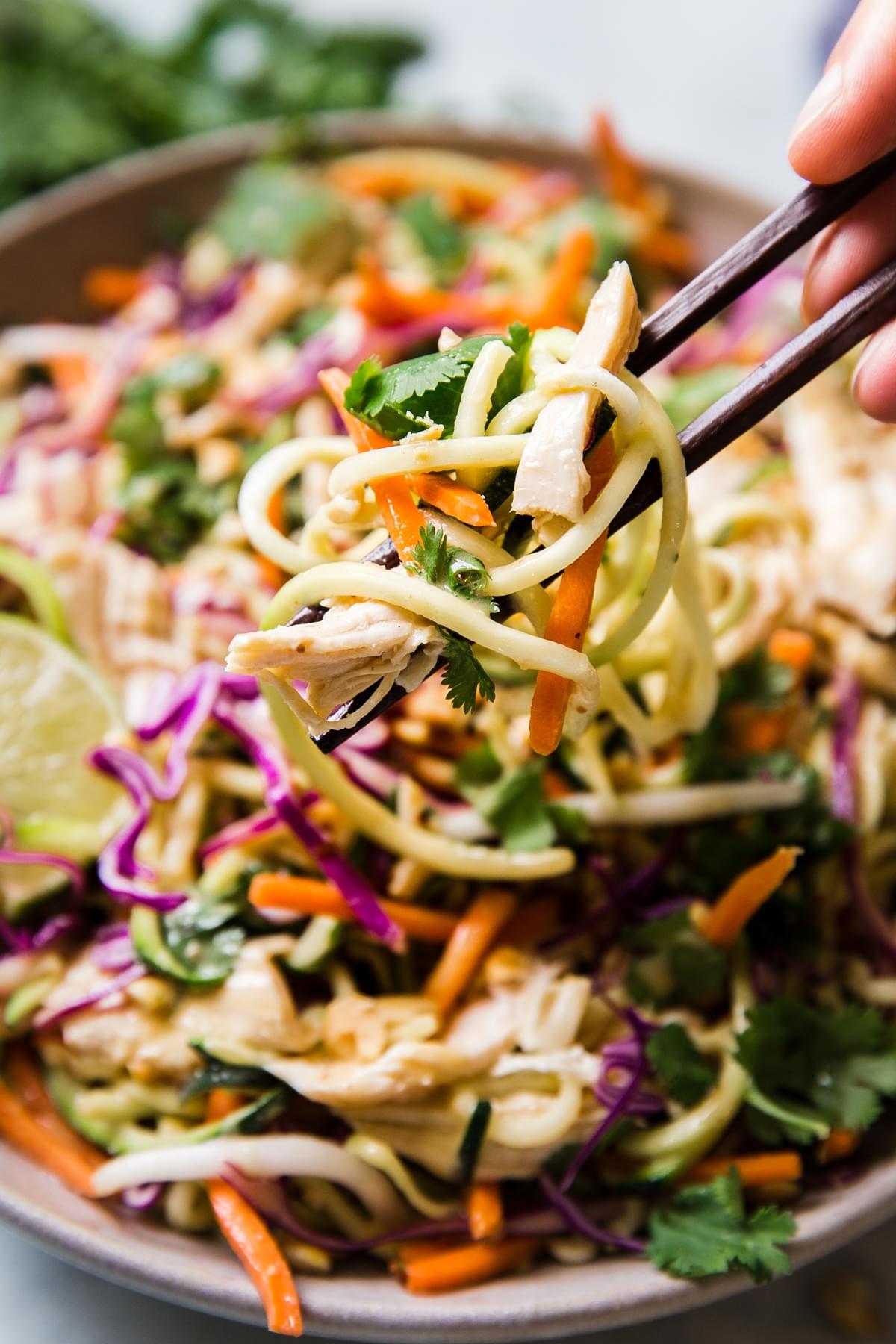 Thai Zucchini Noodle Salad being scooped up with wooden chop sticks from a bowl