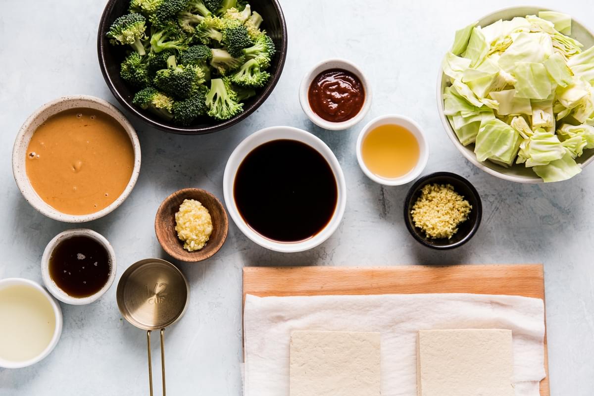 Ingredients laid out for starry broccoli, ginger, garlic, cabbage, peanut sauce, tofu