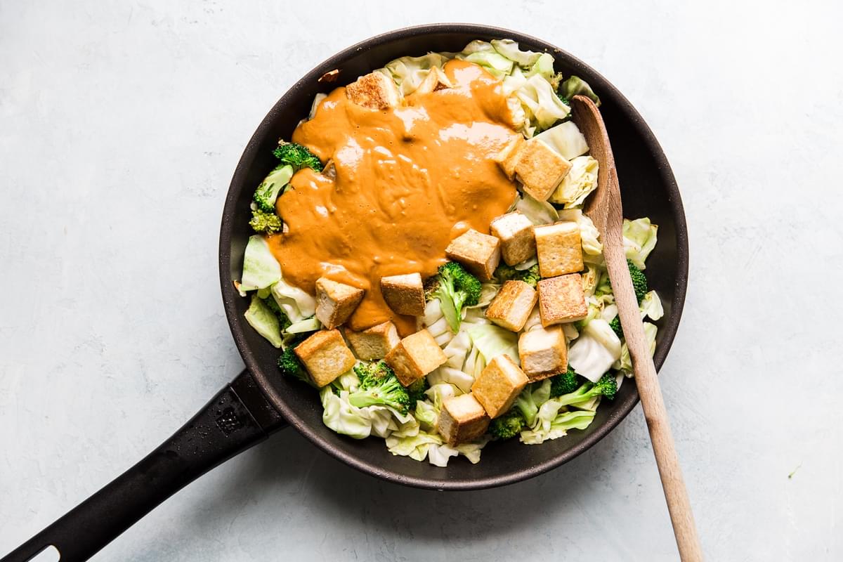 Tofu Stir Fry With Broccoli And Cabbage and peanut sauce in a pan with a wooden spoon