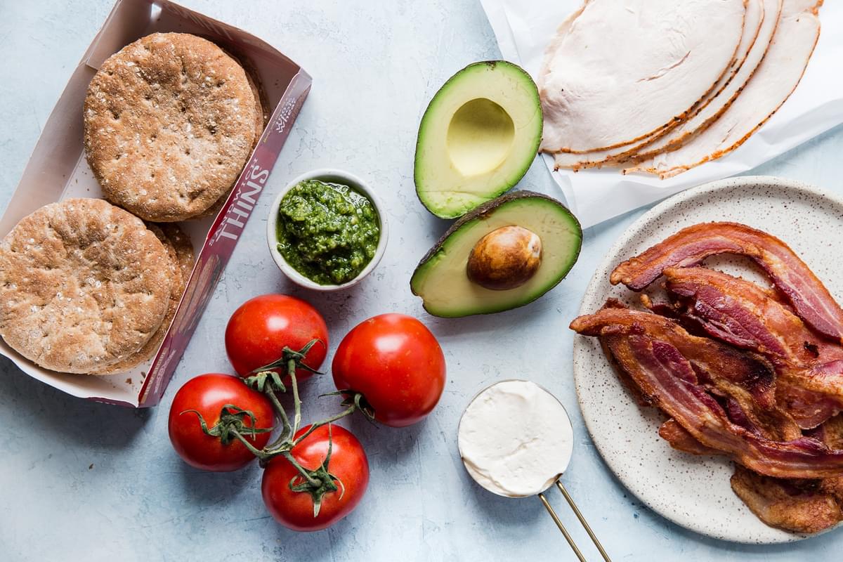 ingredients laid out for Turkey Bacon Club Sandwich avocado, pesto bread and mayonnaise