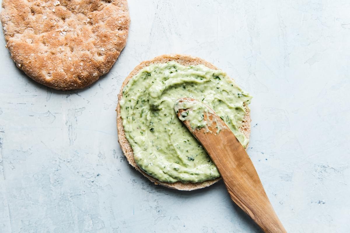 pesto mayonnaise being spread out on a piece of bread
