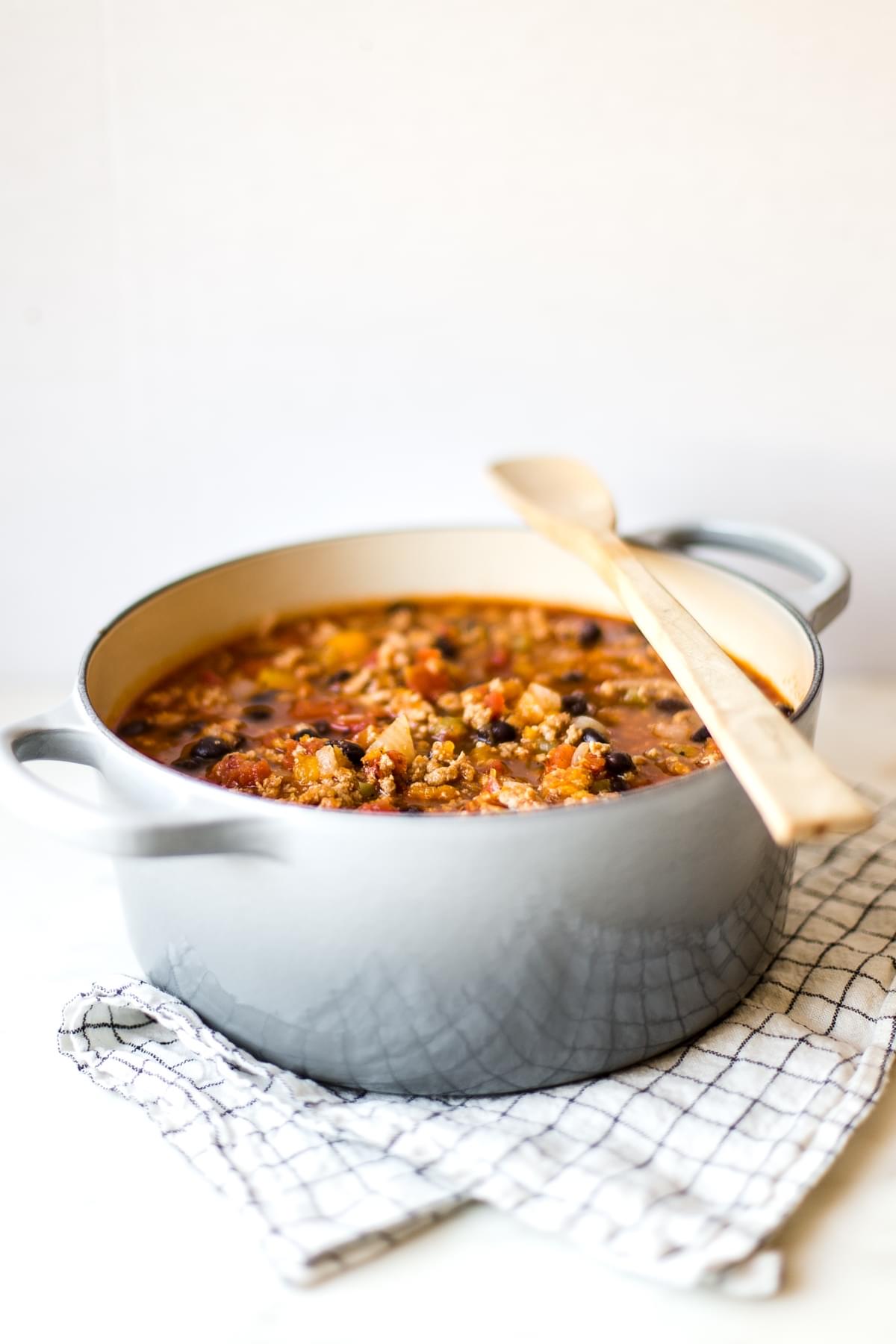 large pot of simple turkey pumpkin chili recipe topped with a wooden a spoon