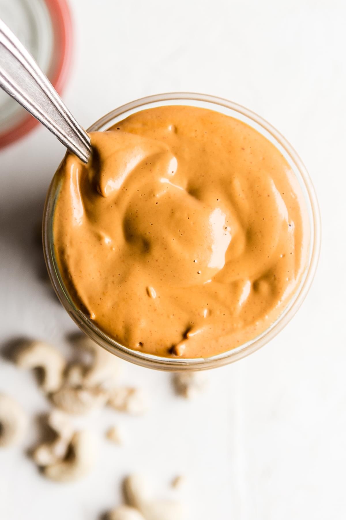 homemade Vegan Cashew Cheese Sauce in a jar with a spoon made with cashew, tomato paste, nutritional yeast and spices