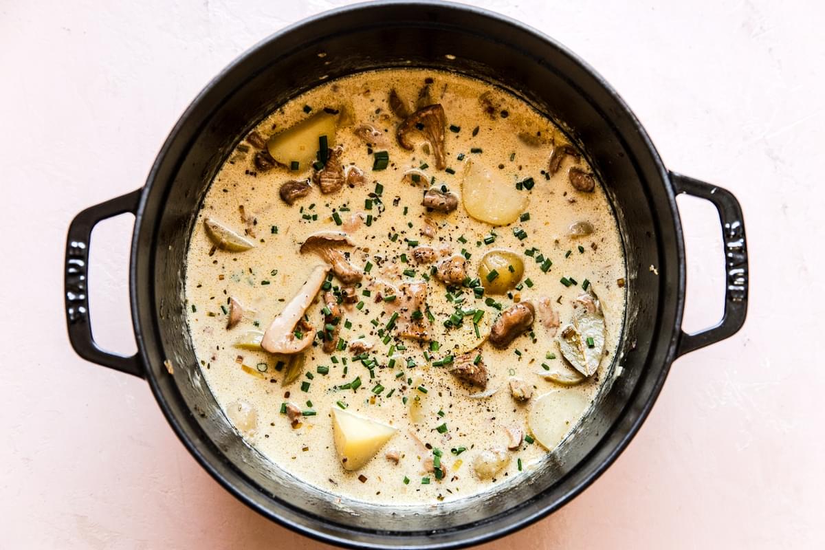 wild mushroom soup in a large pot topped with fresh chives