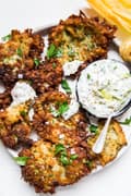 Mediterranean Style Zucchini Fritters With Tzatziki Dipping Sauce on a plater