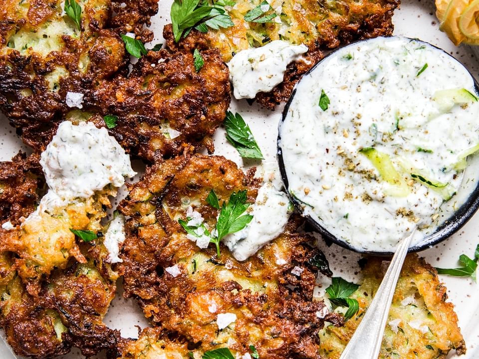 Mediterranean Style Zucchini Fritters With Tzatziki Dipping Sauce on a plater