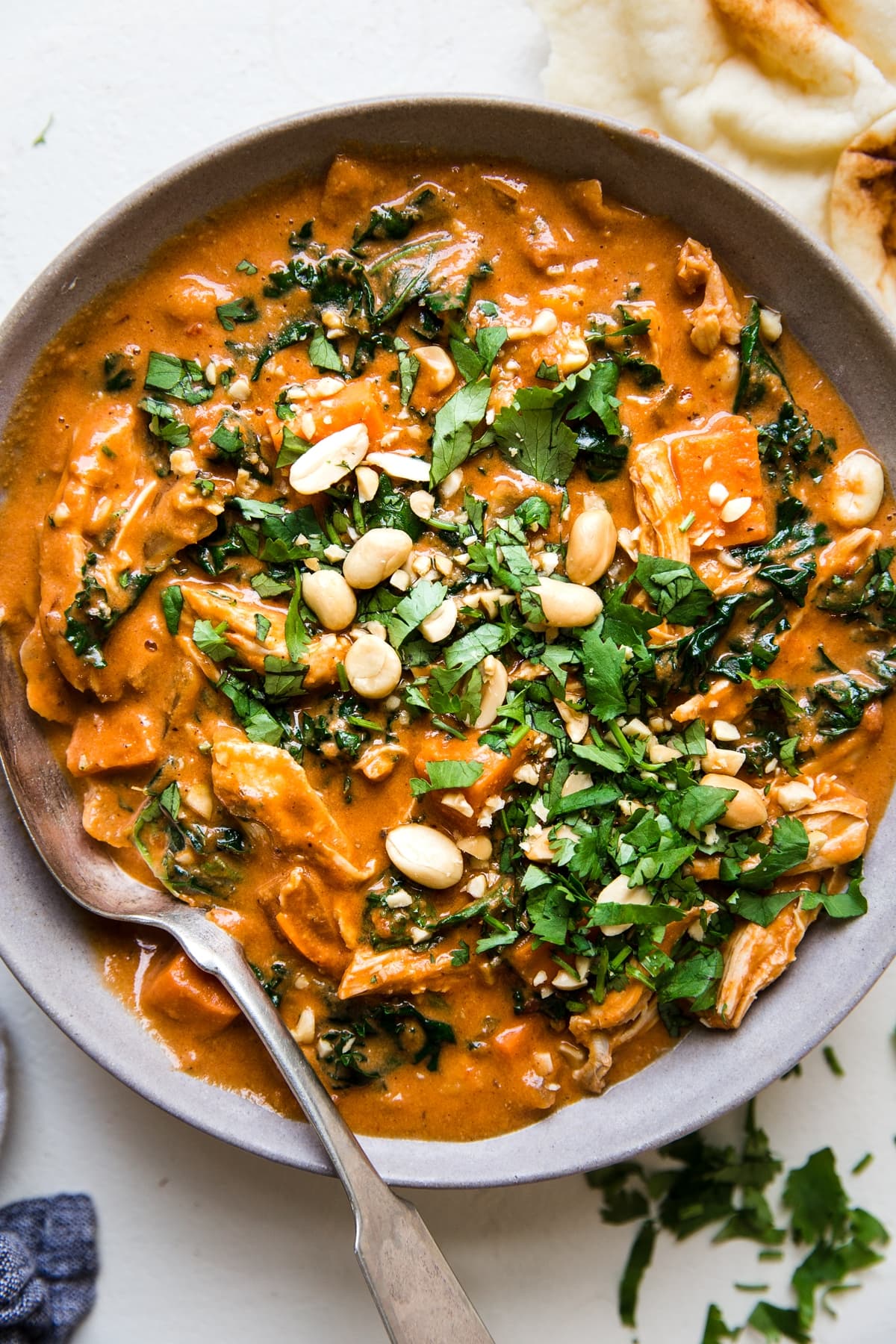 African Peanut Soup in a bowl with ginger, garlic, cumin, crushed tomatoes, sweet potatoes, chickpeas, chicken, kale.