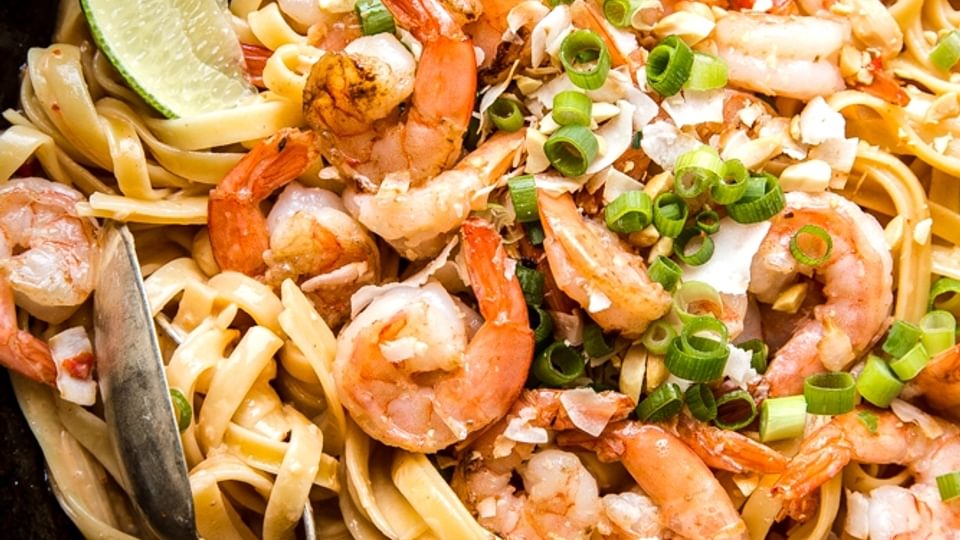 Bang Bang shrimp pasta in a pan with limes and a crazy sauce