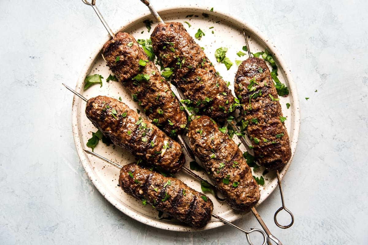 6 beef kofta skewers on a plate topped with parsley