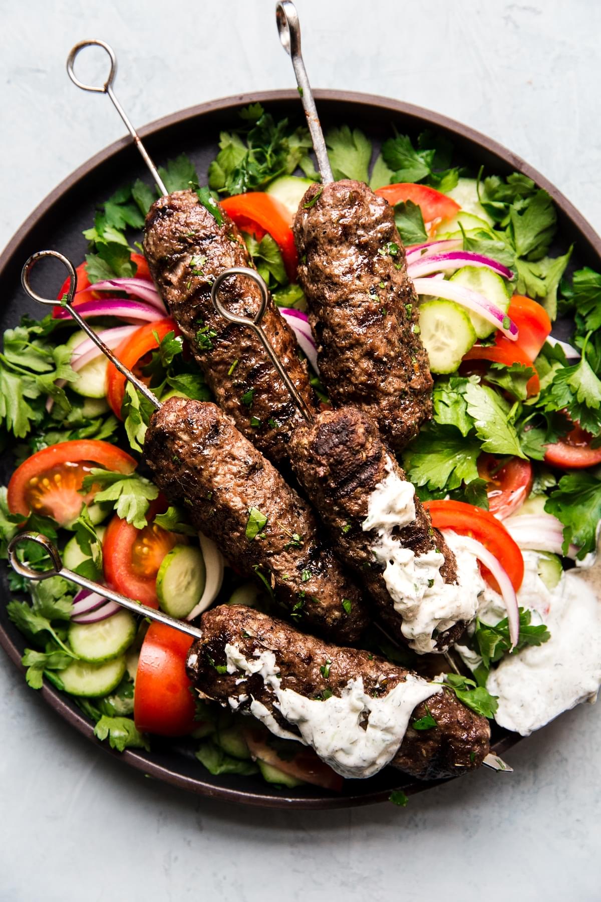 Beef Kofta Kababs with Tzatziki pita bread tomatoes on skewers on a plate