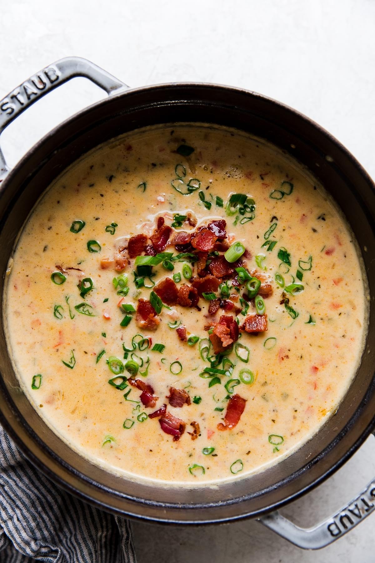 beer cheese soup with bacon, jalapeño, and green onions in a soup pot