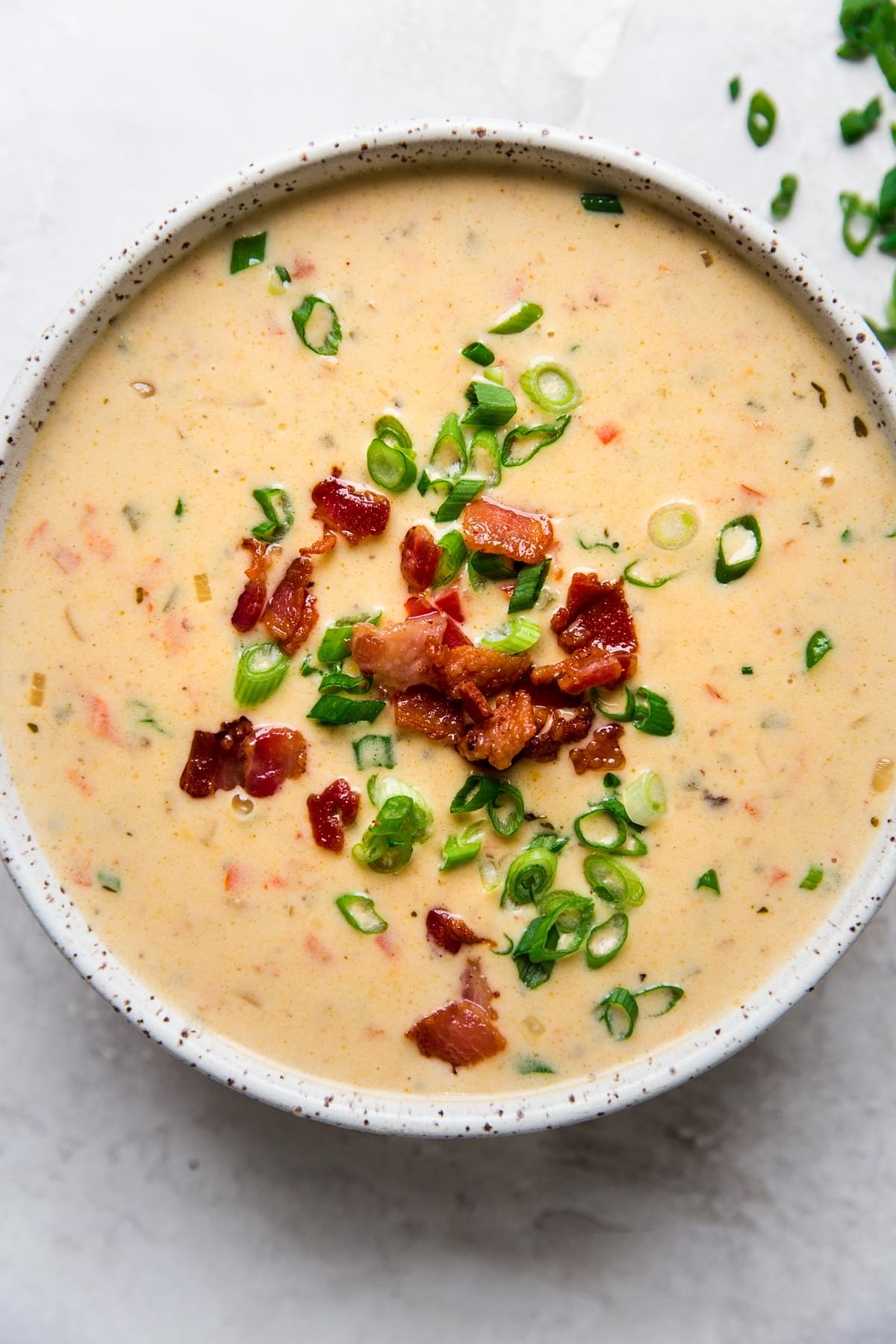 Beer Cheese Soup with bacon, peppers in a bowl with green onions