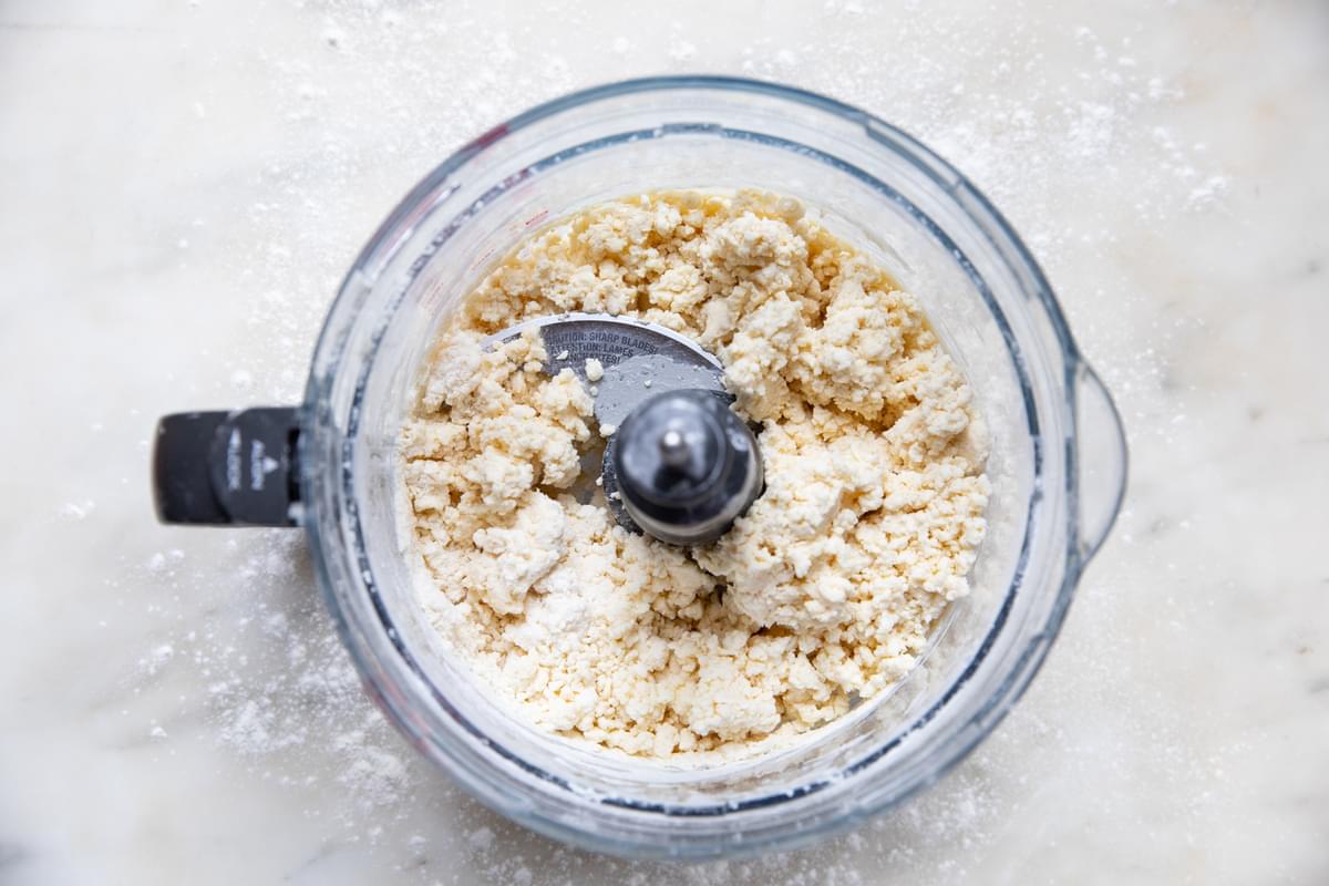flour, butter, baking soda, baking powder, salt and buttermilk being pulsed in a food processor for homemade biscuits
