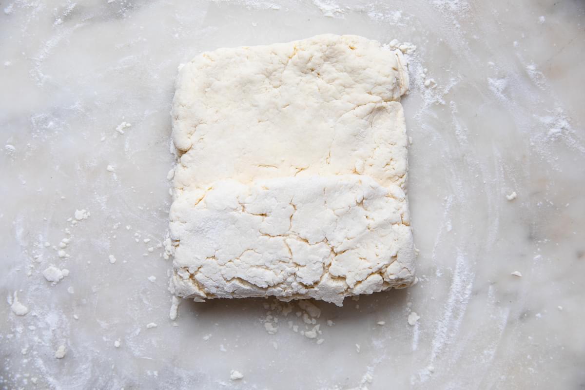 homemade buttermilk biscuit dough on a floured surface pressed into a 1 inch thick rectangle