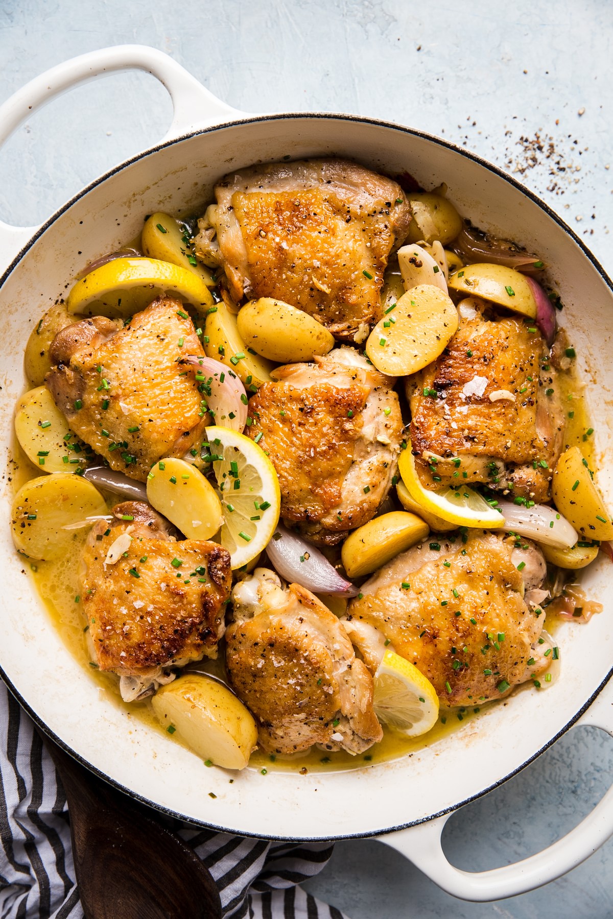 Braised Chicken with Potatoes, shallots, lemons in a white braiser with Chive Butter Sauce
