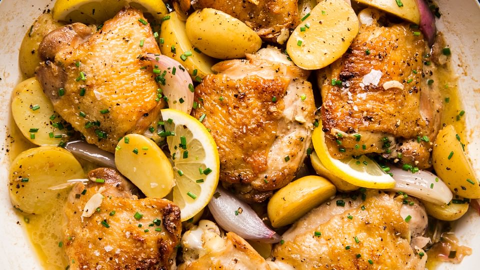 Braised Chicken with Potatoes, shallots, lemons in a white braiser with Chive Butter Sauce