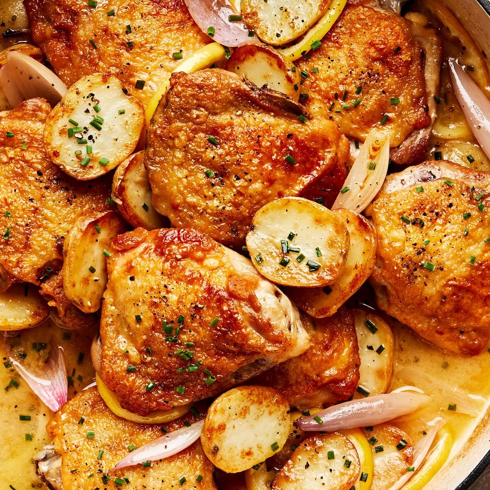 Braised chicken with potatoes and chive butter sauce in a braising dish